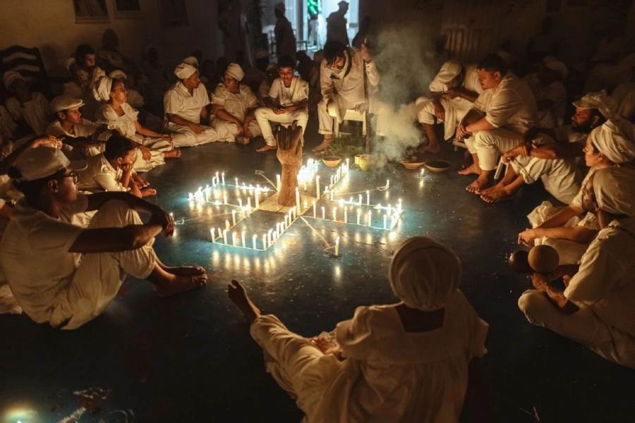 pessoas sentadas no chão em volta de velas