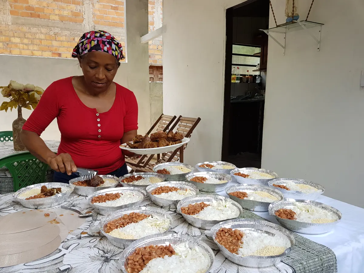 mulher colocando comida em quentinhas